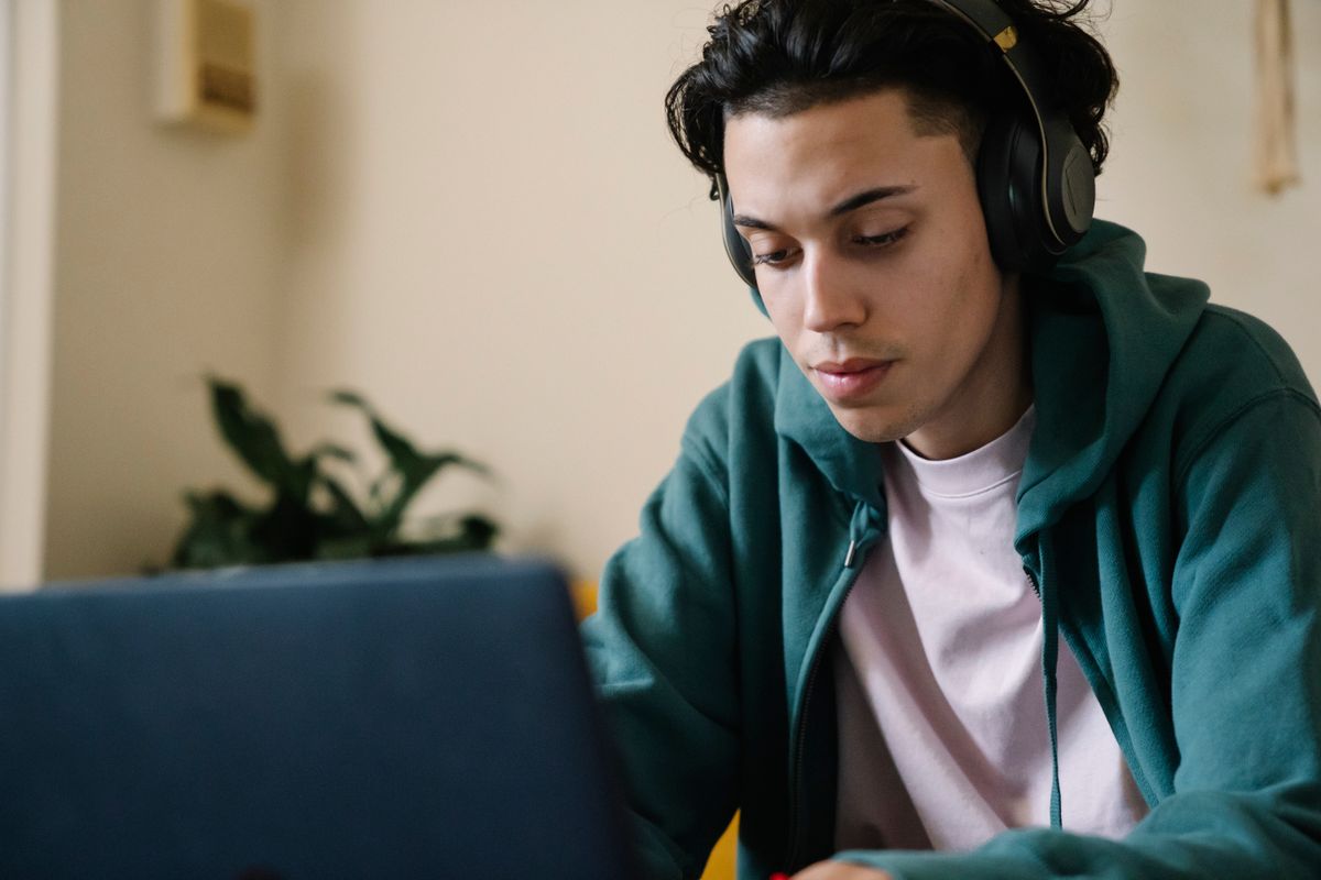 Student wearing headphones studying on a laptop for the TOEFL